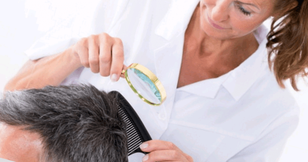 the doctor examines the psoriasis on the head